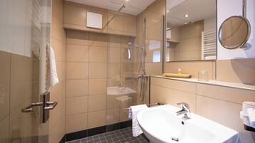 A modern bathroom with a glass-enclosed shower, a white sink, and a mirror.