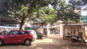 Escena callejera con coches aparcados y una motocicleta, un árbol, y un edificio con un letrero que dice 'ANGEL TATTOO'.