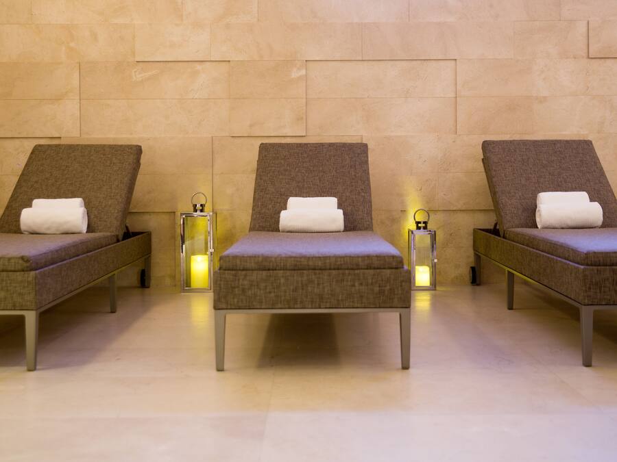 Three reclining chairs with towels, set against a tiled wall with a warm light source between them.