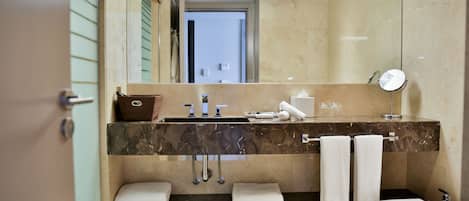Un baño moderno con lavamanos de mármol, inodoro y espejo.