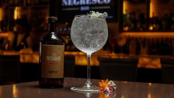 Una botella de Bosque Nativo y un vaso con hielo y flores sobre una barra.