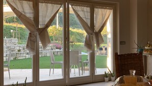 A room with large sliding glass doors leading to a patio with outdoor furniture and potted plants. - B&B Case Pacifici (Ascoli Piceno)
