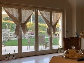 A room with large sliding glass doors leading to a patio with outdoor furniture and potted plants.