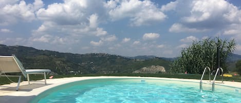 Una piscina al aire libre, sillones reclinables de piscina