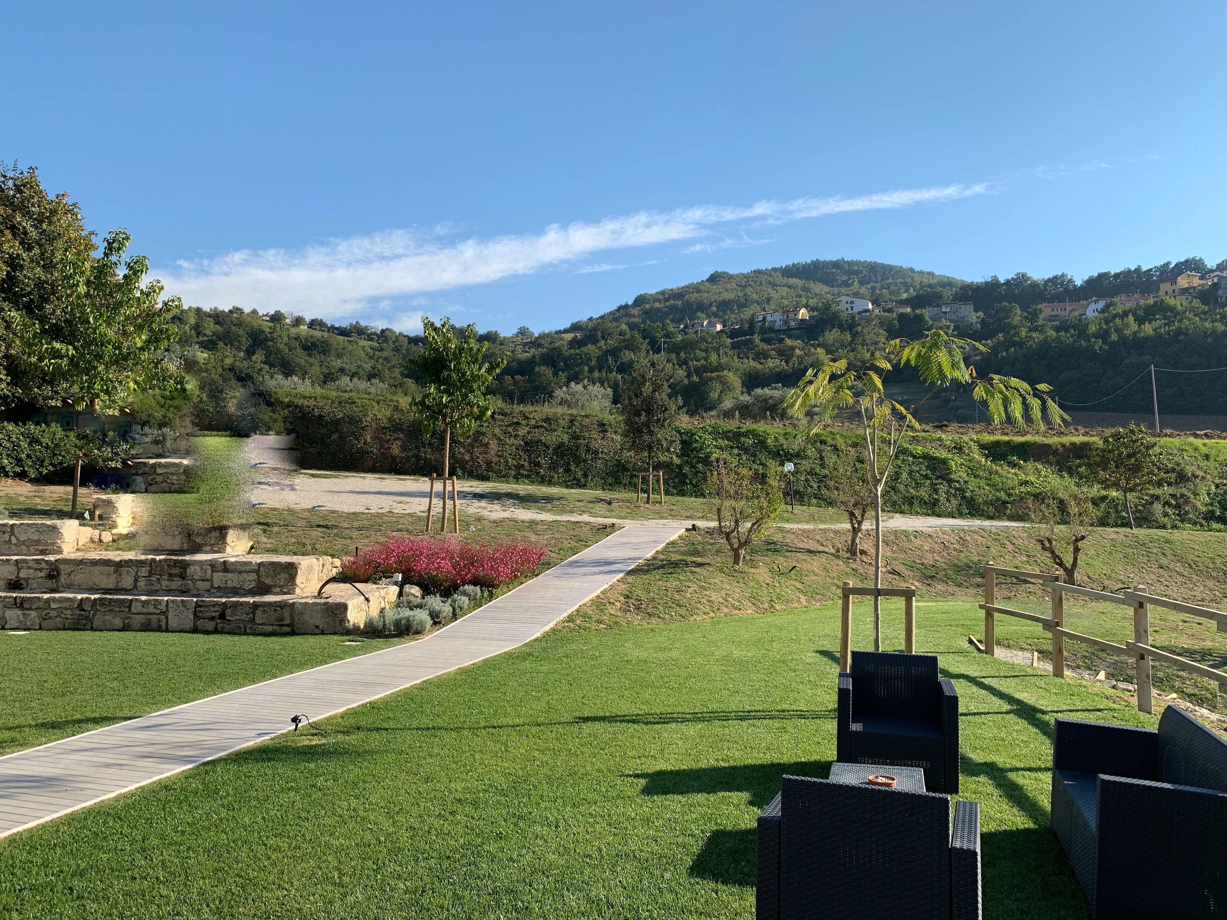 Un sendero atraviesa un área ajardinada con vistas a una colina y edificios distantes.