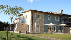 A two-story house with stone and plaster walls, a tiled roof, and a paved patio with outdoor furniture. - B&B Case Pacifici (Ascoli Piceno)
