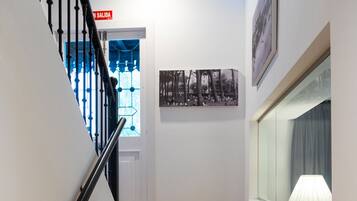 A wooden staircase with black balusters, a handrail, and a red exit sign.