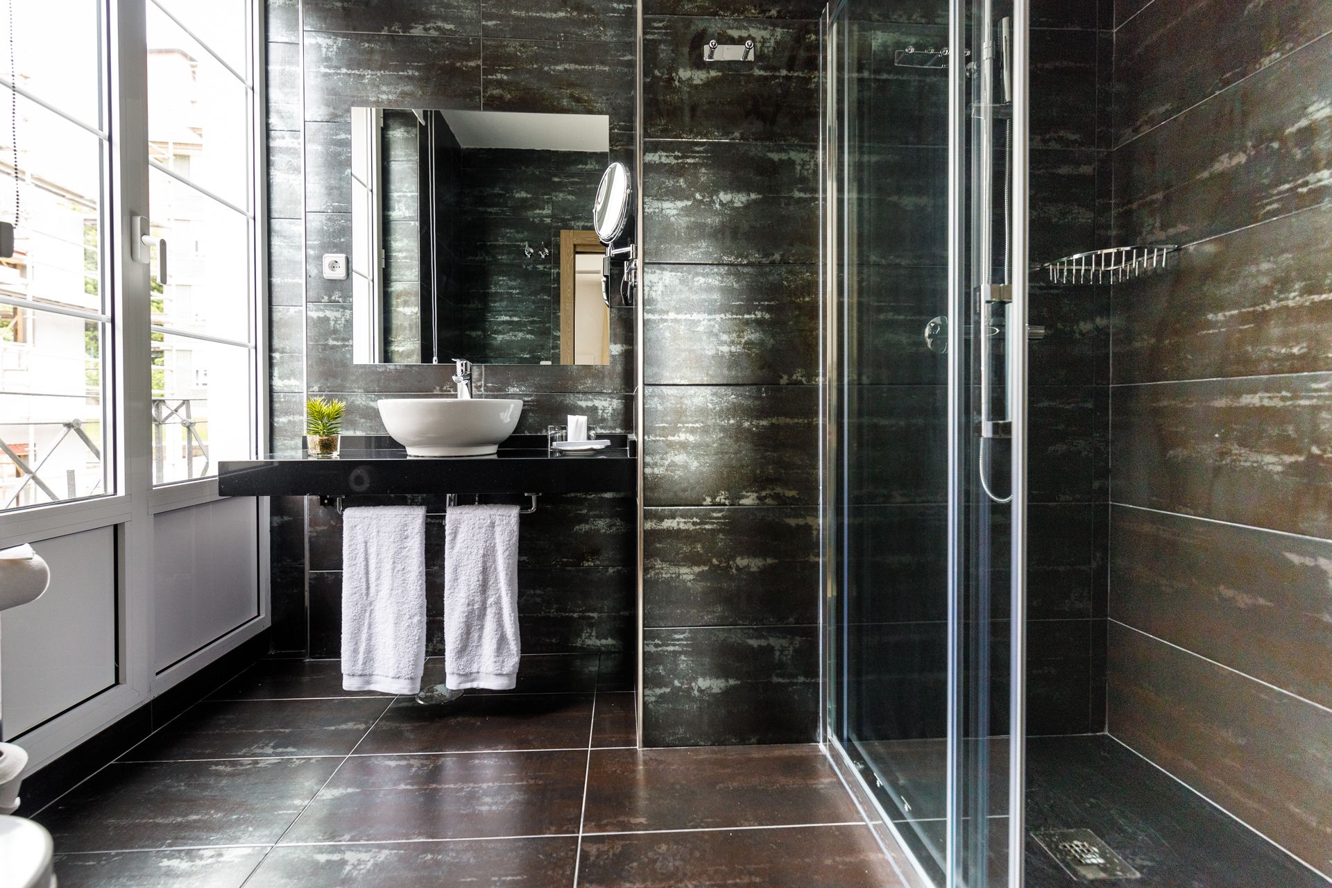 Une salle de bain moderne avec une douche à parois de verre, un grand lavabo et un miroir au-dessus.
