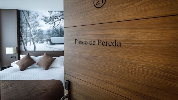 A hotel room with a wooden headboard labeled "21 Paseo de Pereda". - Suite Home Pinares (Santander)
