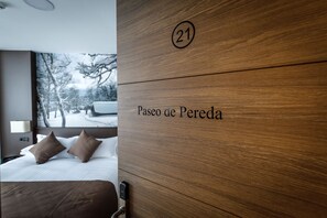 A hotel room with a wooden headboard labeled "21 Paseo de Pereda". - Suite Home Pinares (Santander)