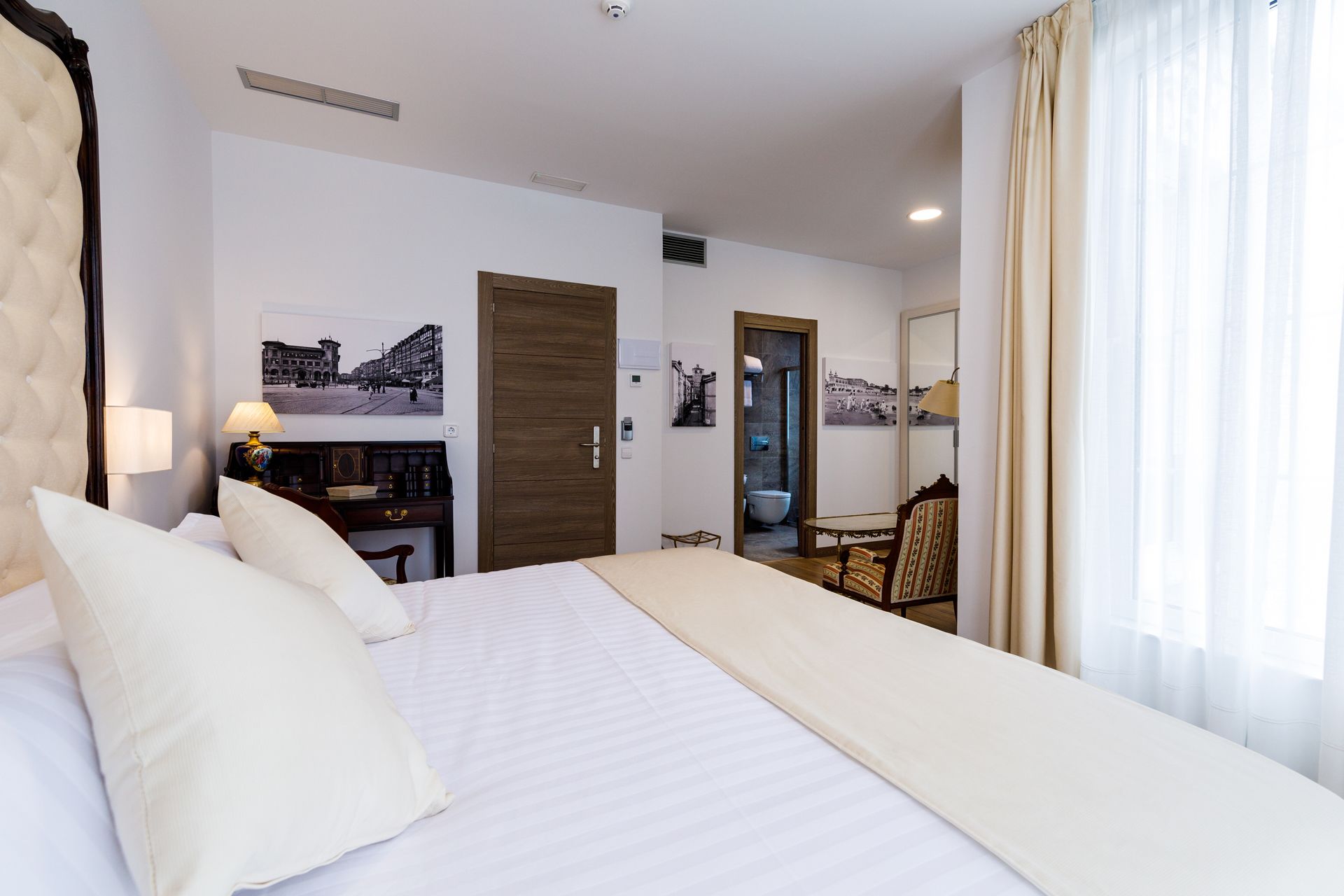 Ein Hotelzimmer mit einem großen Bett, einem Schreibtisch, einem Stuhl und einem durchgegangenen Badezimmer.