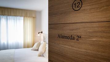 A hotel room with a bed, a nightstand, and a wooden wall with the number 12 and the name "Alameda 2a".