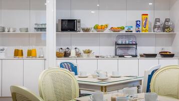 Cocina moderna con armarios blancos, un microondas, una cafetera y diversos alimentos en estantes.