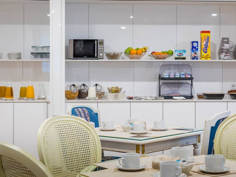 Cocina moderna con armarios blancos, un microondas, una cafetera y diversos alimentos en estantes.