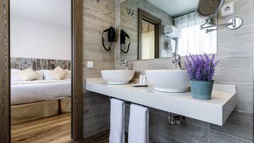 Une salle de bain moderne avec deux vasques, un grand miroir et un plant de lavande en pot.
