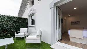 A modern hotel room with a glass door leading to a balcony, a bed, and a small seating area with a table and chairs. - Suite Home Pinares (Santander)