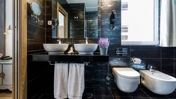 Een moderne badkamer met twee wastafels, een bidet en een toilet.