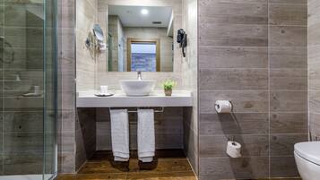 Un baño moderno con un espejo grande, un lavabo blanco y una cabina de ducha de vidrio.