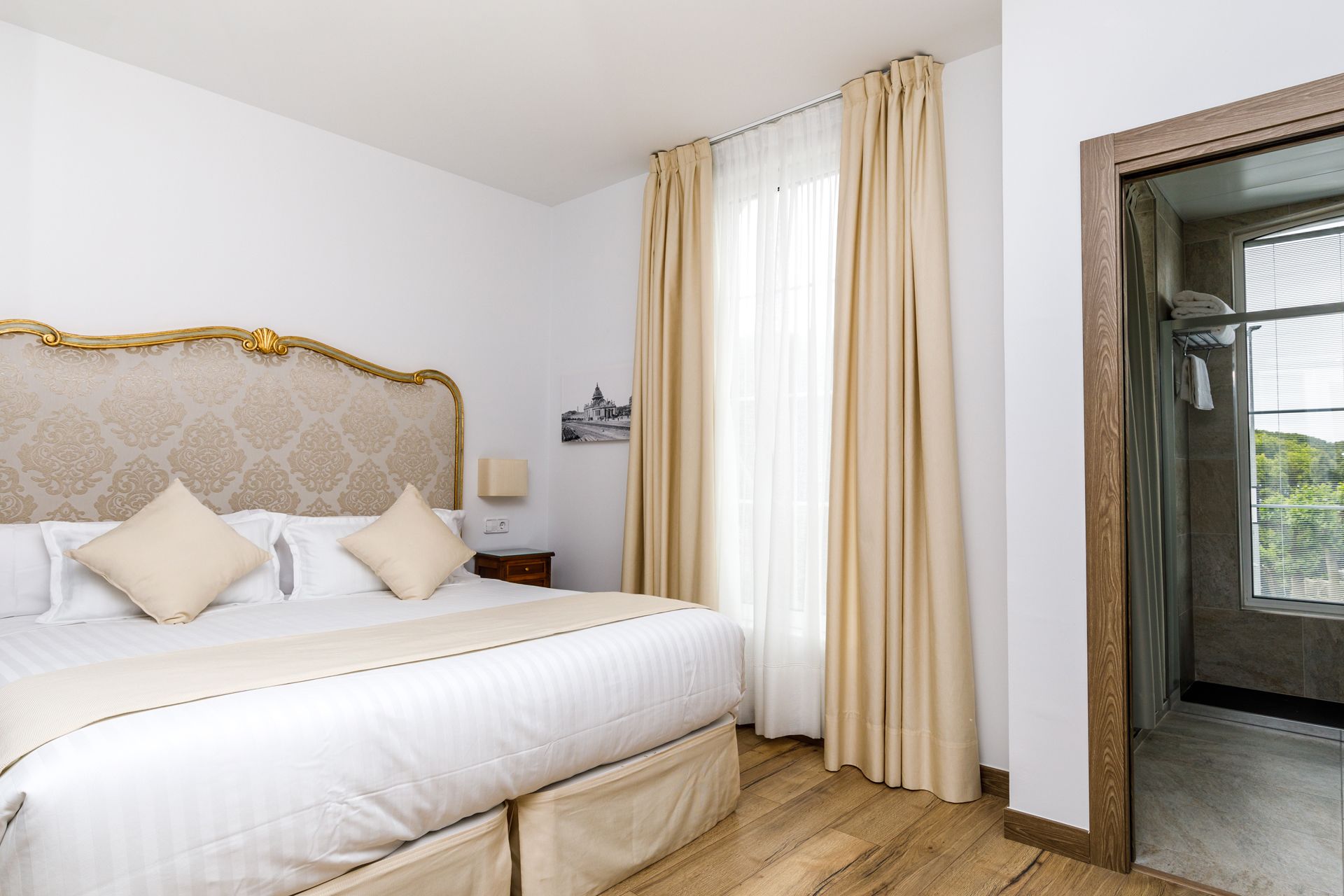 Una habitación de hotel con una cama, una mesita de noche, una lámpara y vistas a un balcón.