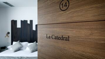 A hotel room with a bed, pillows, and a wooden panel with the number 14 and the name "La Catedral".