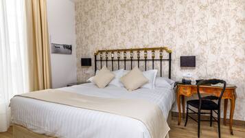 Una cama bien hecha con cabecera, una mesita de noche con lámpara y una silla.