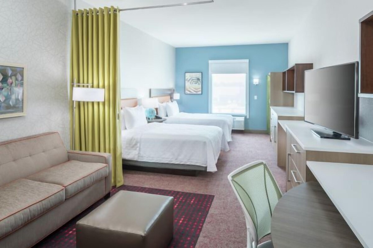 A hotel room with a bed, a sofa, a TV, and a desk.