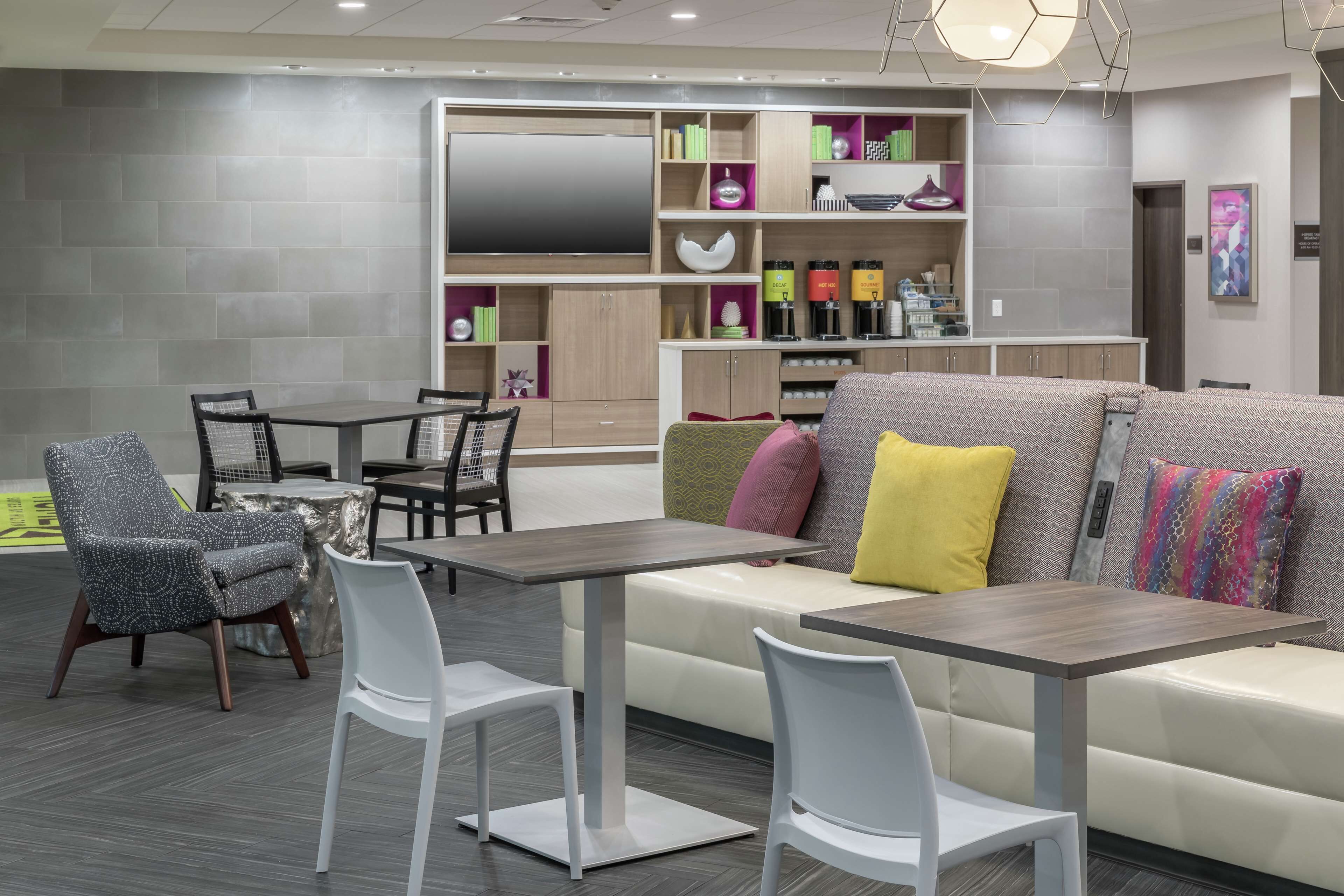 Un espace de détente moderne comprenant un canapé, des fauteuils, une table et un téléviseur.