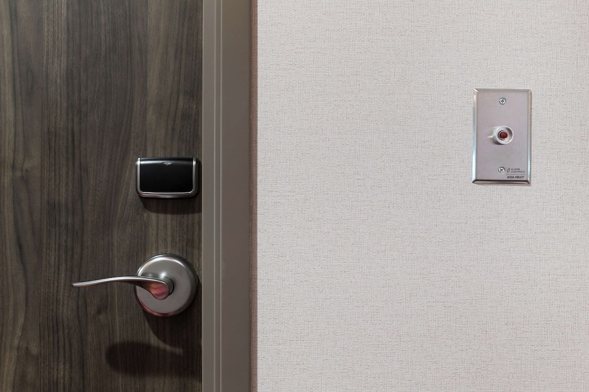 A door with a modern lock and a small electronic device on the wall.