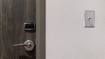 A door with a modern lock and a small electronic device on the wall.