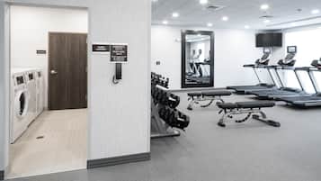 Une salle de sport équipée de tapis de course, d’haltères et d’un miroir.