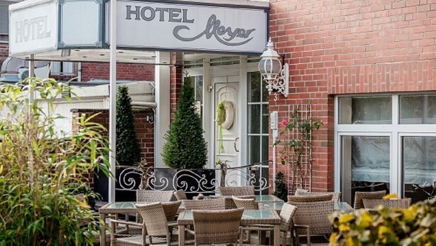 A hotel with outdoor seating and a brick facade. - Hotel Meyer (Bergheim)