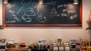A chalkboard with multilingual greetings and food illustrations, a buffet with various dishes and condiments, and a modern pendant light fixture. - Hotel Meyer (Bergheim)