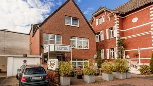A hotel with a red brick facade, a signboard, and a parked car. - Hotel Meyer (Bergheim)