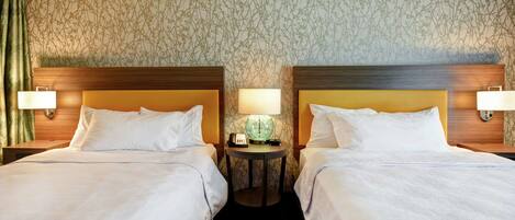 A hotel room with two beds, a round table with a globe and a clock, and a patterned wallpaper.