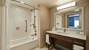 A modern bathroom with a bathtub, shower, vanity with a mirror, and a towel rack.