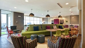 Een moderne zithoek met een groene bank, gestreept fauteuils en een kleine tafel.