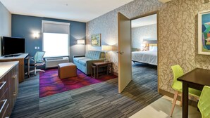 Een hotelkamer met een bureau, een bank, een bed en een eethoek.