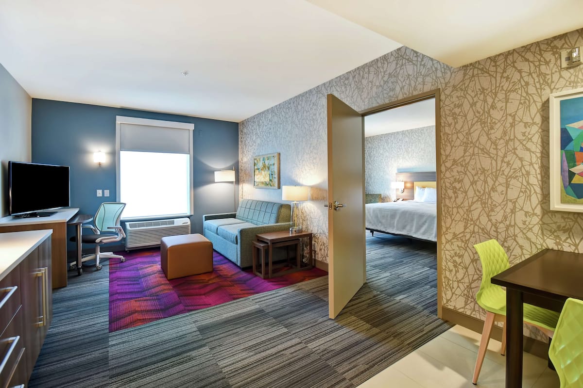 Een hotelkamer met een bureau, een bank, een bed en een eethoek.