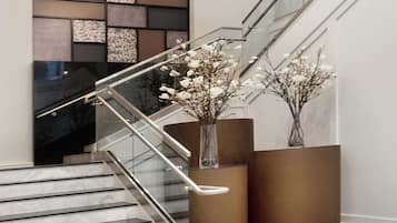 Una escalera moderna con barandillas de vidrio y un diseño geométrico en la pared.