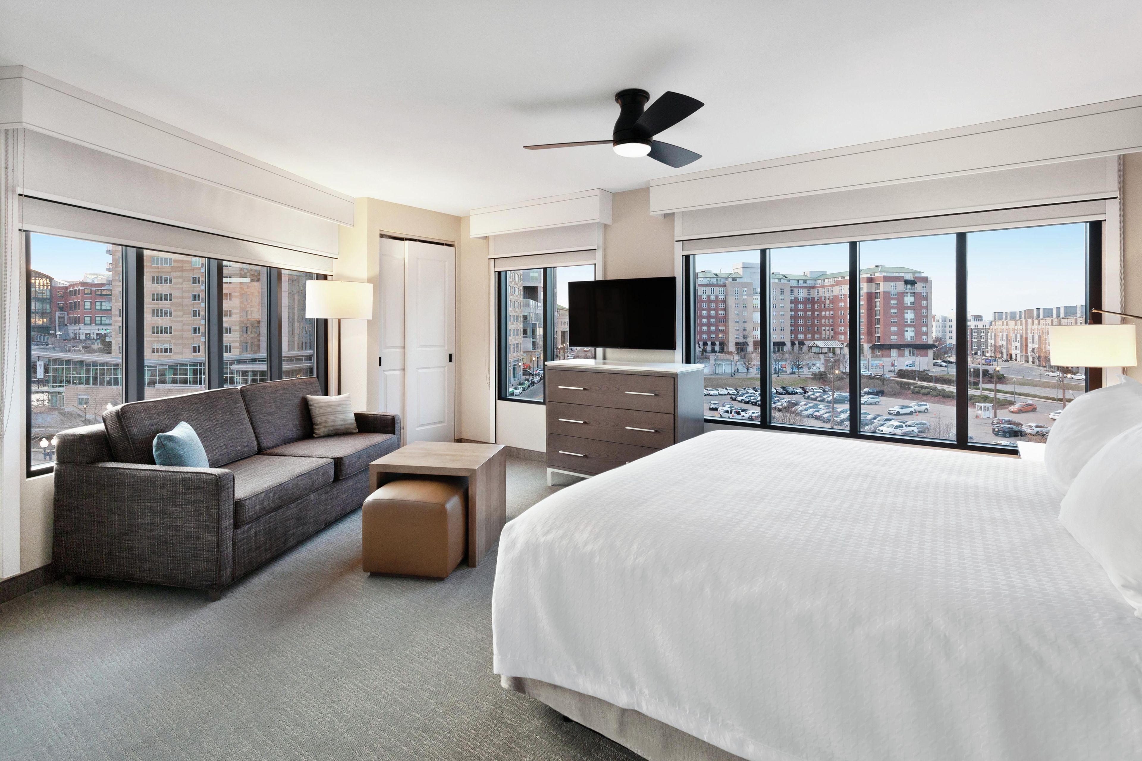Ein modernes Hotelzimmer mit einem großen Bett, einer Schlafcouch, einem Schreibtisch und einem Fernseher.