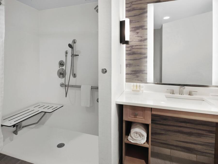 A modern bathroom with a walk-in shower, a vanity with a mirror, and a towel rack.