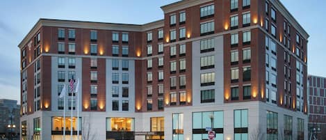 A multi-story hotel with a brick facade, large windows, and a sign for "Homewood Suites."