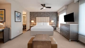A hotel room with a bed, a desk, a television, and a ceiling fan.