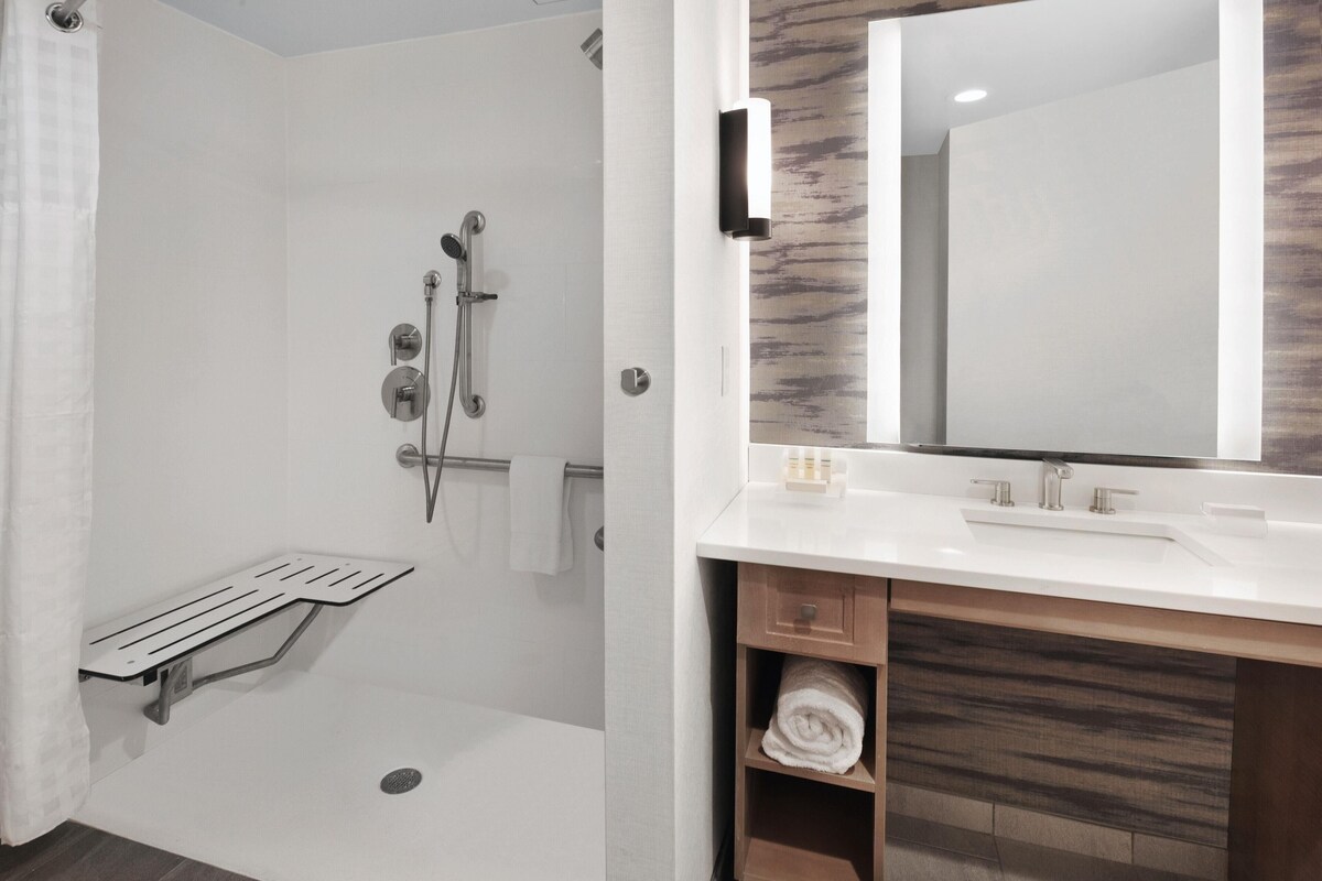 Une salle de bain moderne avec une douche, un lavabo et un miroir.