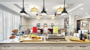 A modern hotel breakfast area with a buffet setup, including a variety of food items and a wine selection. - Homewood Suites by Hilton Providence Downtown (Providence)