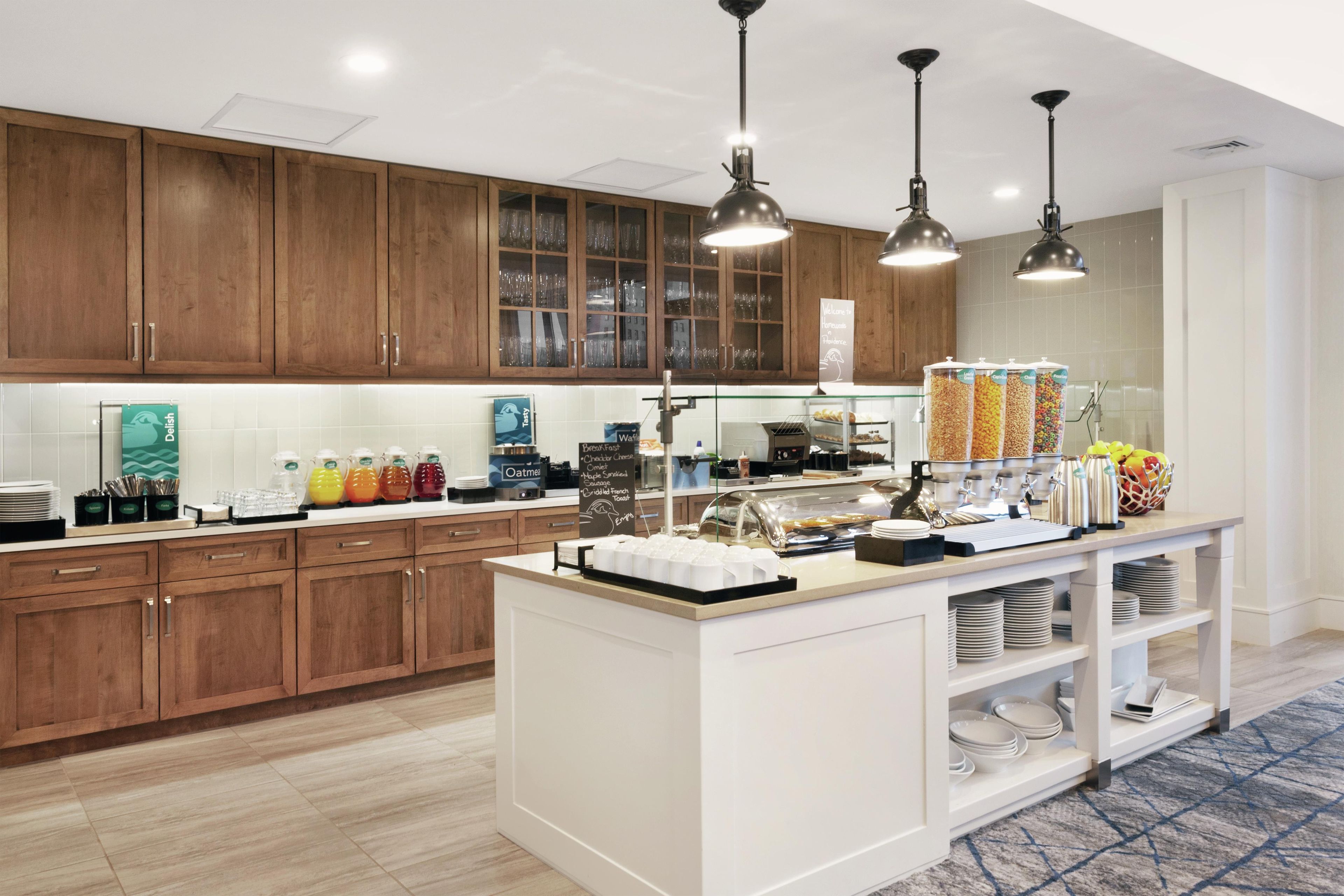 A modern kitchen with wooden cabinets, a breakfast bar, and various food dispensers.