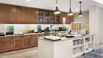 A modern kitchen with wooden cabinets, a breakfast bar, and various food dispensers.