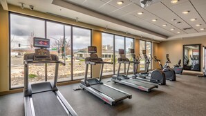 Un gimnasio con cintas de correr, bicicletas estáticas y un espejo.