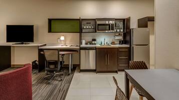 A compact hotel room with a kitchenette, a dining area, and a TV.