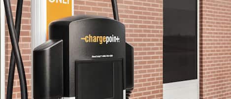 An EV charging station with a brick building in the background.